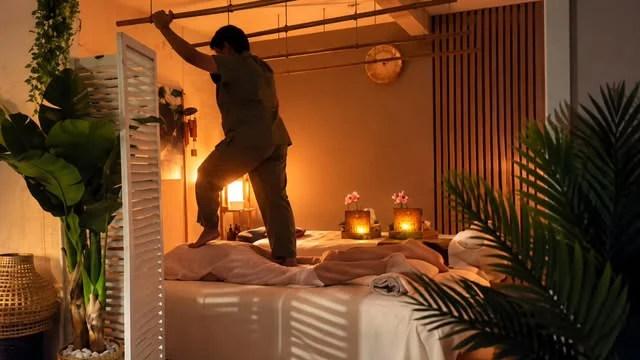 Terapeuta de Hilot Filipino realizando un masaje en una cabina con luz cálida y plantas